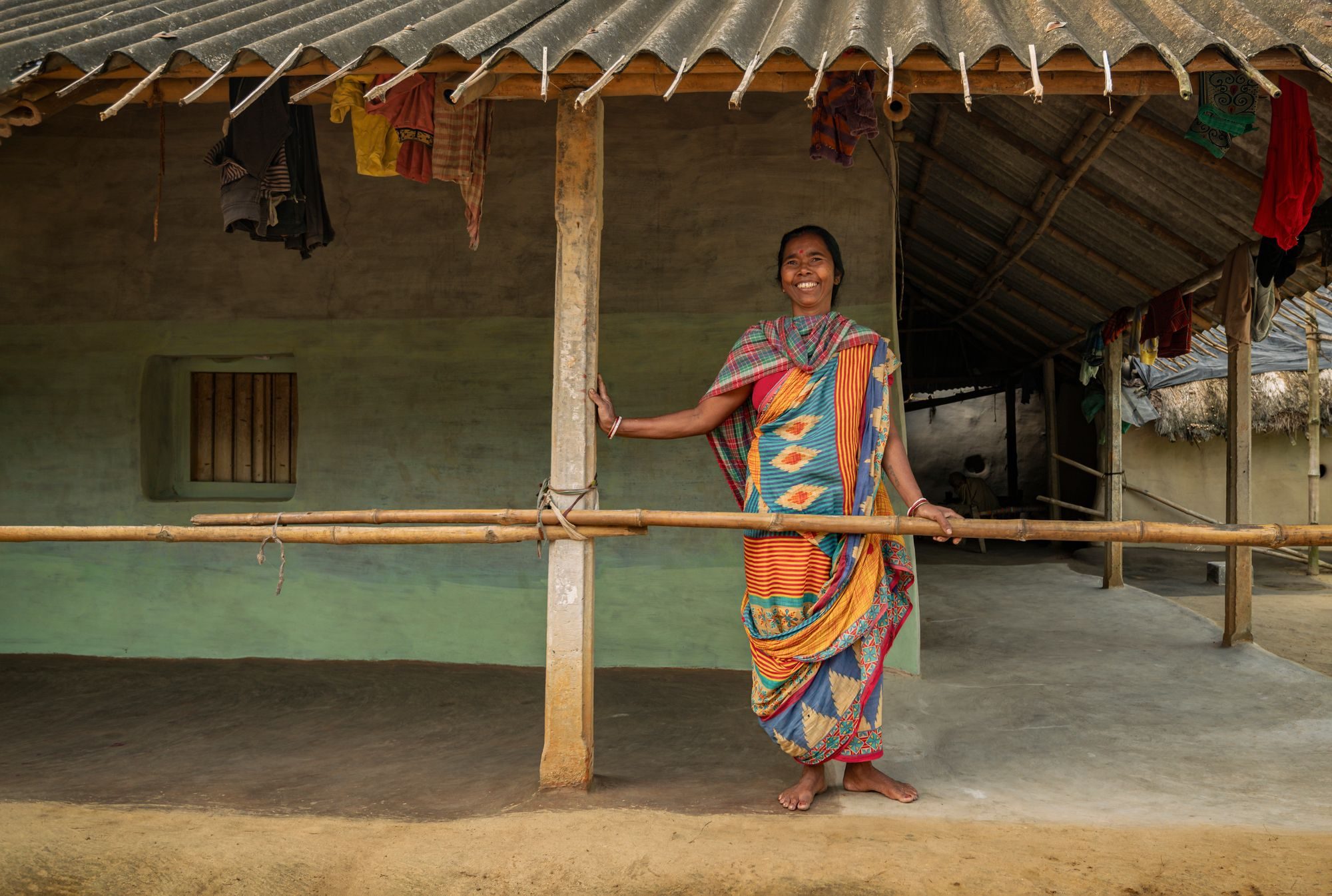 A woman in a rural Indian village standing at the doorway of her home