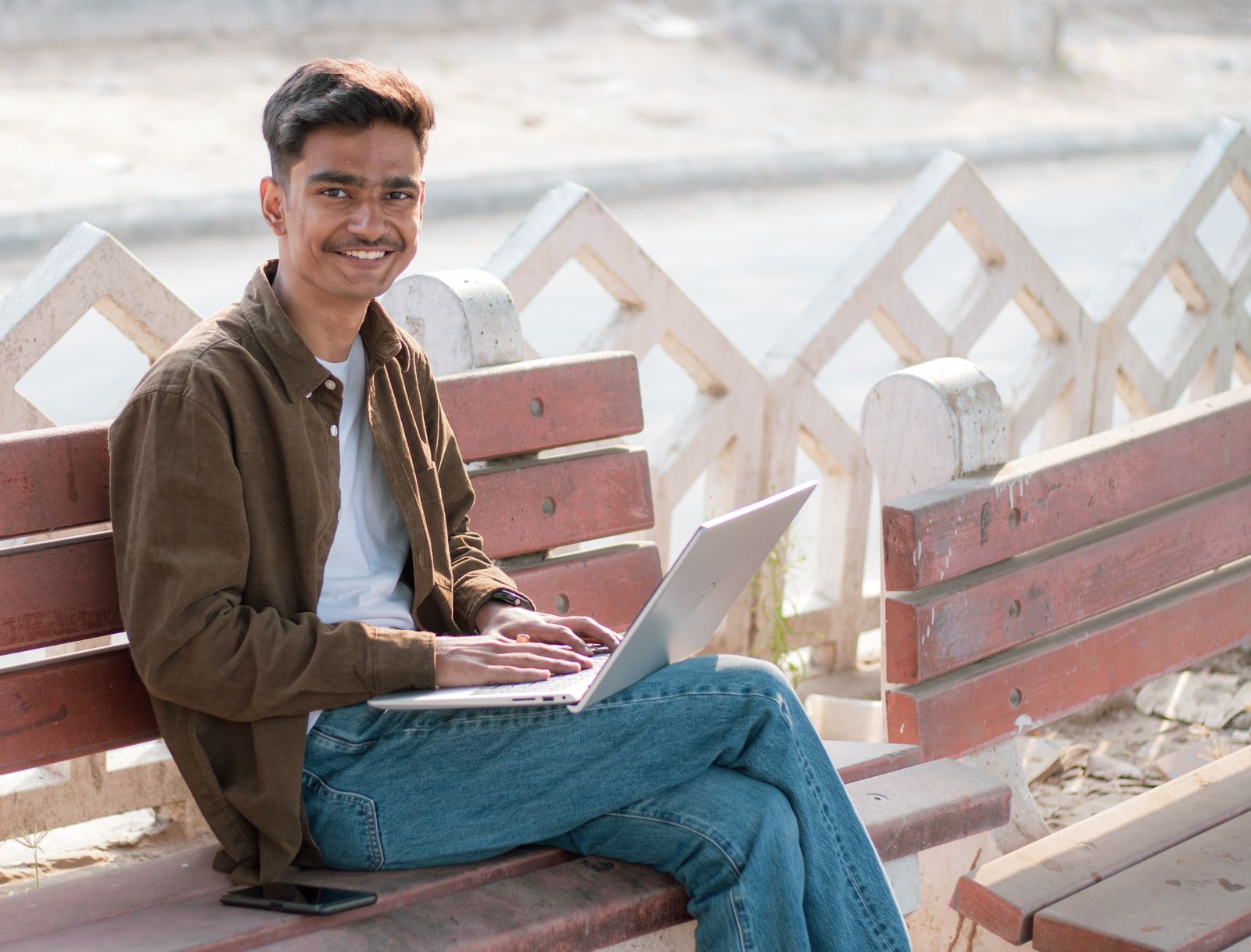 A young man in Telangana working on a laptop outdoors
